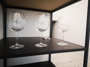 tres copas de vino sentadas en una estantería negra en Apartamenty LENA 3, en Racibórz