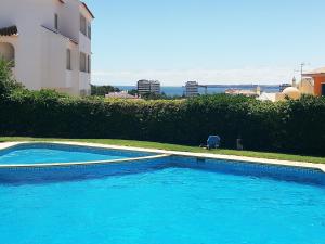 une grande piscine bleue à côté d'un bâtiment dans l'établissement Amoreira Mar, Alvor - Praia e Piscina, à Alvor