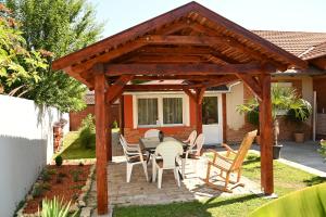drewniana pergola ze stołem i krzesłami w obiekcie Pálma Apartman w mieście Gyula