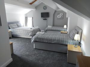 a small bedroom with two beds and a tv at Ambrose Hotel in Barrow in Furness