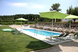 a swimming pool with chairs and a green umbrella at Quinta da Chapeleira em Azeitão in Azeitao