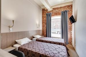 Duas camas num pequeno quarto com uma janela em Nabokov Loft-Hotel em Rostov on Don