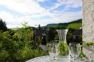 dois copos de vinho e um vaso sentado numa mesa em Grüne Wohlfühloase mit einmaliger Aussicht em Königswinter