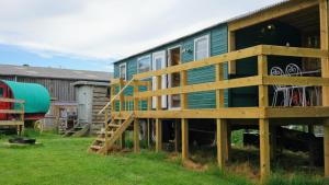 a house with a staircase in a yard at Unique Upcycled Straw Trailer Westcote in Hawick