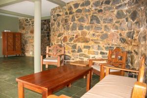 Habitación con pared de piedra, mesa de madera y sillas. en Hostel La Isla en Pipa