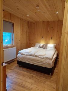 a bedroom with a large bed in a wooden wall at Greystone summerhouse in Egilsstadir