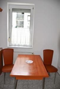 a wooden table with two chairs and a window at Pilikán Apartments Lenti in Lenti