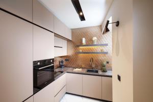 a kitchen with white cabinets and a brick wall at Premium Apartments with balcony in Rijeka