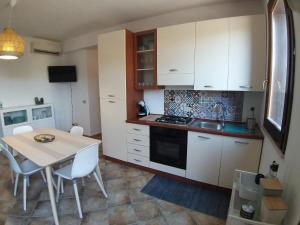 a kitchen with white cabinets and a table with chairs at IL VIAGGIO DI COSIMO in San Vito lo Capo
