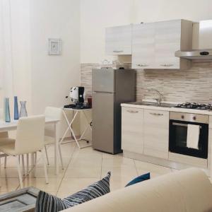 Una cocina con refrigerador y una mesa con sillas. en Cerasella house, en Castellammare di Stabia