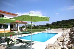 a swimming pool with a green umbrella and chairs at Quinta da Chapeleira em Azeitão in Azeitao