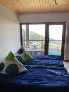 a bedroom with a blue bed with a large window at Overpoint Panorama in Sasbachwalden