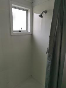 a bathroom with a shower and a window at Barbwire Bach in Opunake