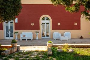 a building with white chairs and a red wall at Dimora dei nonni 199 in Monopoli