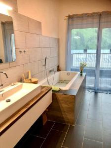 La salle de bains est pourvue d'une baignoire, d'un lavabo et d'une fenêtre. dans l'établissement Villa Alma Arlberg, à Warth am Arlberg