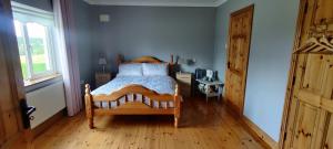 een slaapkamer met een bed en een houten vloer bij Colmán House in Kilmihil
