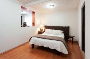 een slaapkamer met een groot bed en een houten vloer bij Suite 5A, Altavista, Garden House, Welcome to San Angel in Mexico-Stad