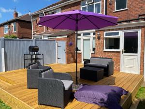 a purple umbrella sitting on a wooden deck with chairs at The Homestead House in Doncaster