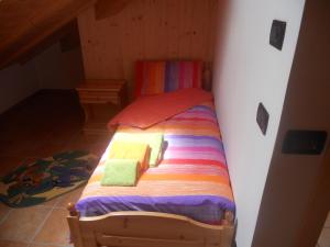 Una cama pequeña con sábanas coloridas y toallas. en Agritur Melango, en Fondo