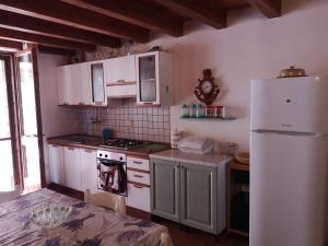 La cuisine est équipée de placards blancs et d'un réfrigérateur blanc. dans l'établissement House by the sea, à Gonnesa