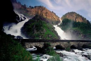 a bridge over a river with a waterfall at Seljestad Cottages in Skare