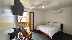 1 dormitorio con 1 cama, TV y ventana en Pousada Ancoradouro, en Abraão