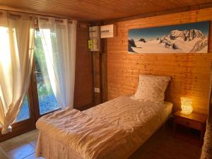 a bedroom with a bed and a large window at Le petit chalet des Greys in Meillerie