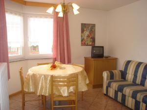 a living room with a table and a couch and a tv at Appartamenti Villa Maria in Canazei