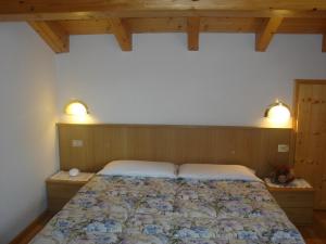 Una cama en un dormitorio con dos luces encima. en Appartamenti Villa Maria, en Canazei