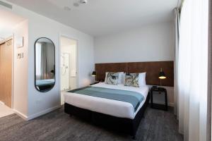 ein Schlafzimmer mit einem großen Bett und einem Spiegel in der Unterkunft Quest Takapuna in Auckland