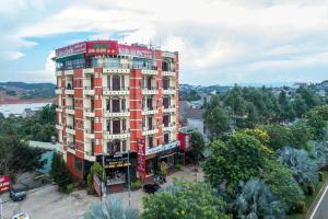 um edifício vermelho numa rua da cidade com árvores em Sai Gon Dak Nong Hotel em Gia Nghĩa