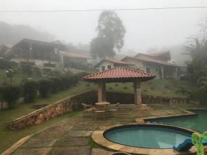 a house with a swimming pool and a gazebo at CHALÉ RECANTO SAGRADO( MONTE VERDE) in Guaramiranga