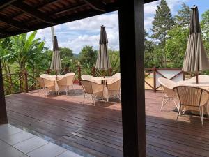 a wooden deck with tables and chairs and umbrellas at CHALÉ RECANTO SAGRADO( MONTE VERDE) in Guaramiranga
