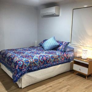 um quarto com uma cama com um edredão colorido em Large Studio Unit Close to Theme Parks em Gold Coast