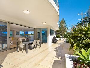 a house with a patio with a table and chairs at Nielsen on the Park Unit 1 3 Bed in Coolangatta