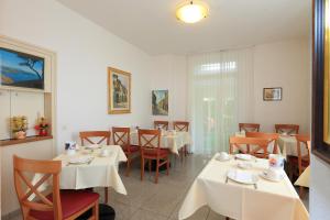 un comedor con mesas y sillas blancas en Hotel Garni dei fiori, en Ascona