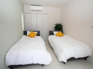 2 camas en una habitación con almohadas blancas y amarillas en Ｖｉｌｌａ・Ｃｈａｒｍｅ, en Motobu