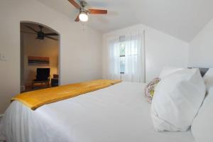 a bedroom with a large white bed with a ceiling fan at Historic w/deck, king bed & air by Lake Michigan in Manistee
