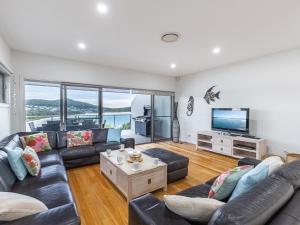 a living room with a couch and a tv at Casa al Mare the jewel of Fingal Bay with stunning views WiFi and Air Conditioning in Fingal Bay