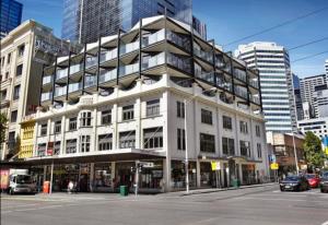 ein großes weißes Gebäude an der Ecke einer Stadtstraße in der Unterkunft ReadySet Apartments at Kett in Melbourne