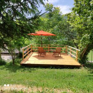 a wooden deck with two chairs and an umbrella at PRENOČIŠČE 9a in Tolmin