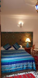 1 dormitorio con 1 cama con manta azul y rayada azul en Riad Konouz, en Marrakech