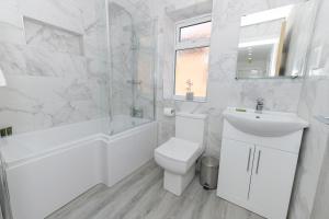 Baño blanco con aseo y bañera en Adbolton House Apartments - Sleek, Stylish, Brand New & Low Carbon en Nottingham