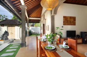 Un comedor con una mesa de madera con sillas. en Sudha Villa Bali B, en Seminyak