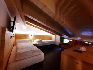 a small room with two beds and a desk at Alpen Hotel Vidi in Madonna di Campiglio