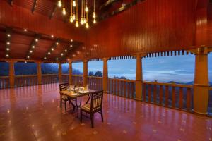 a dining room with a table and chairs on a balcony at Accord Highland Hotel Ooty in Ooty
