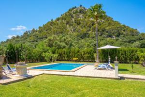 a pool with chairs and an umbrella and a mountain at Villa Emazabel in Pollença