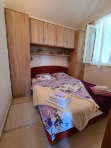Apartmani Božana Viganj في فيغاني: غرفة نوم بسرير ارجواني مع دواليب خشبية