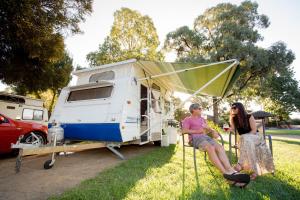 two women and a man are sitting in a tent at Shepparton Holiday Park and Village in Shepparton
