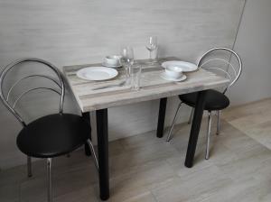 una mesa de madera con 2 sillas, platos y copas de vino en 2 комнатная с новым ремонтом, кондиционером, в самом центре, en Rivne